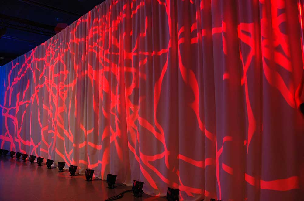 pipe and drape de color blanco iluminado en rojo para separar un espacio